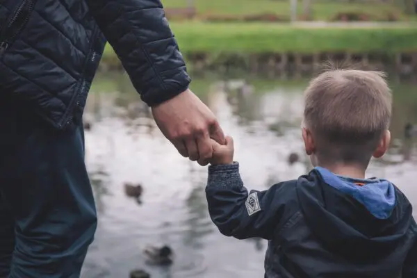 jongetje aan hand vader, kijkend naar water