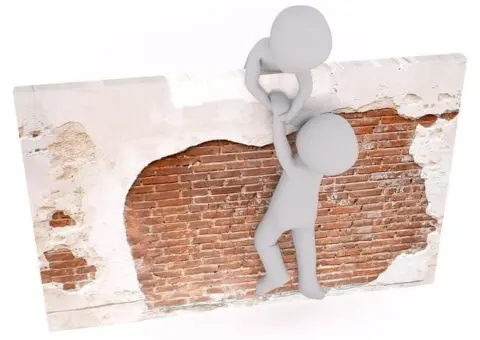 twee poppetjes die met hulp van elkaar over een muurtje klimmen