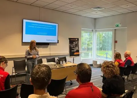 Foto van lezing tijdens de Spierziektedag 2025 met een aandachtig luisterend publiek