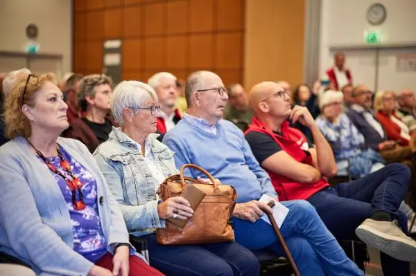 Foto van bezoekers van de Spierziektedag 2025, die luisteren naar een presentatie