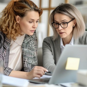 Twee personen aan het werk achter een laptop.