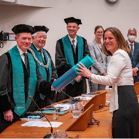 Promotiecommissie (links) overhandigt Christa (rechts) haar bul.