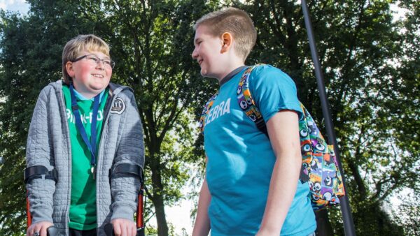 Twee schoolgaande kinderen van de basisschool van wie één met een beperking.