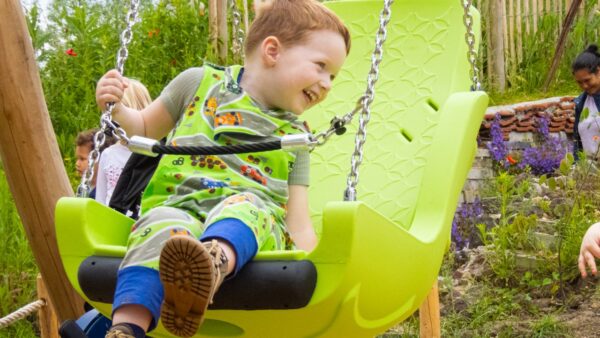 Een blije kleuter met een nog niet gediagnosticeerde ziekte op een schommel