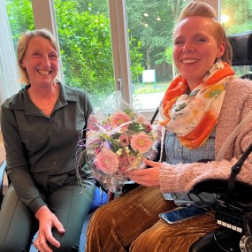 Dr. Anneke van der Kooi neemt een bos roze bloemen in ontvangst