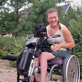 Marieke met haar hulphond Vello op schoot.
