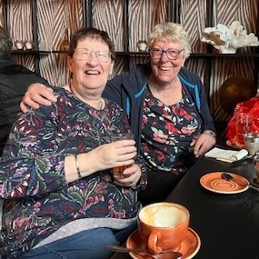 Twee lachende personen zittend naast elkaar