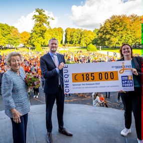 Voormalig koning Beatrix en 2 andere personen nemen cheque van €185.000 in ontvangst.