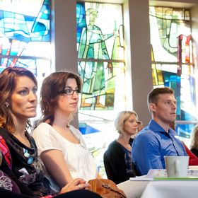 Vier personen luisterend in een zaal